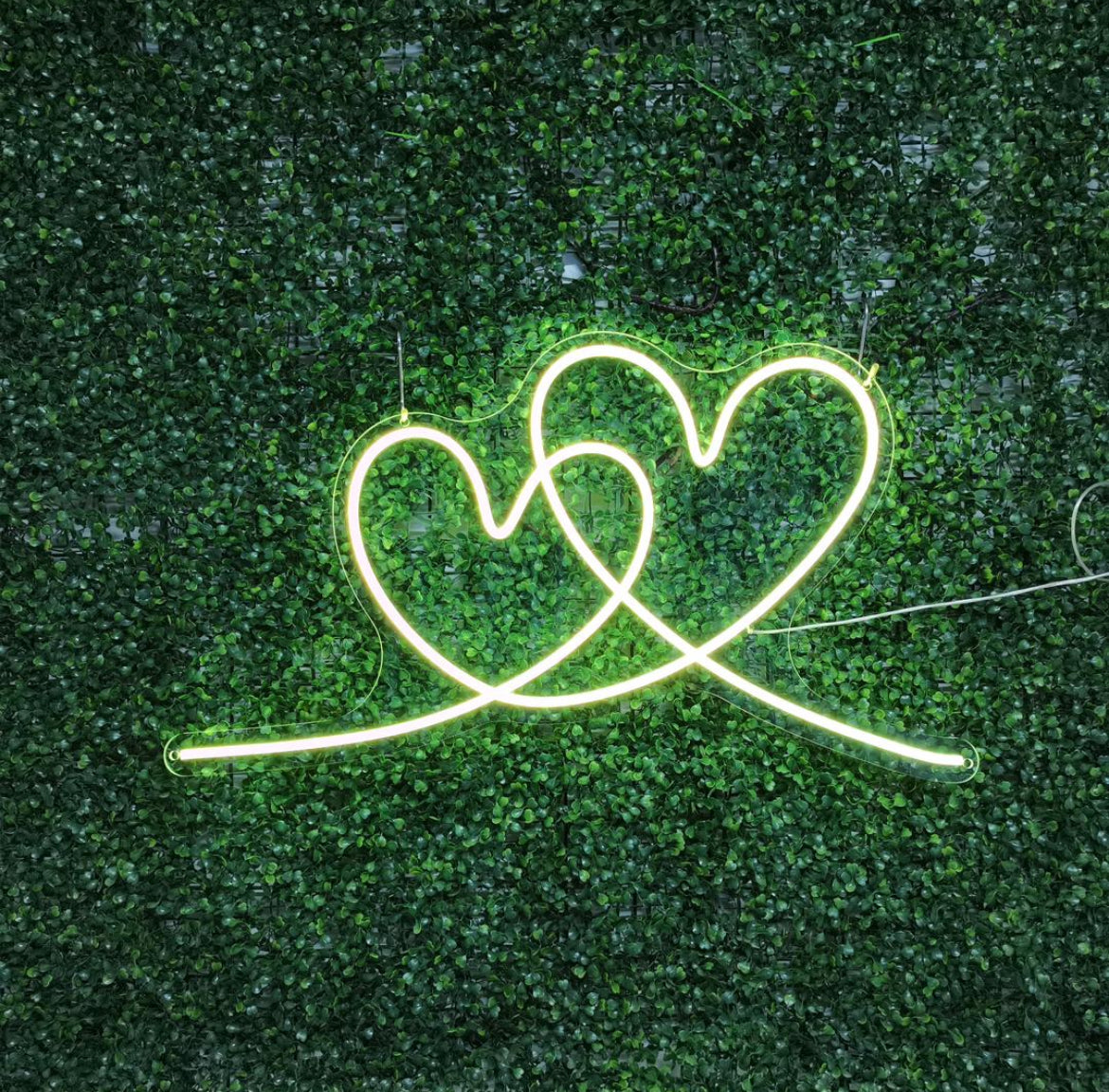 A custom neon light of a green interlocking heart