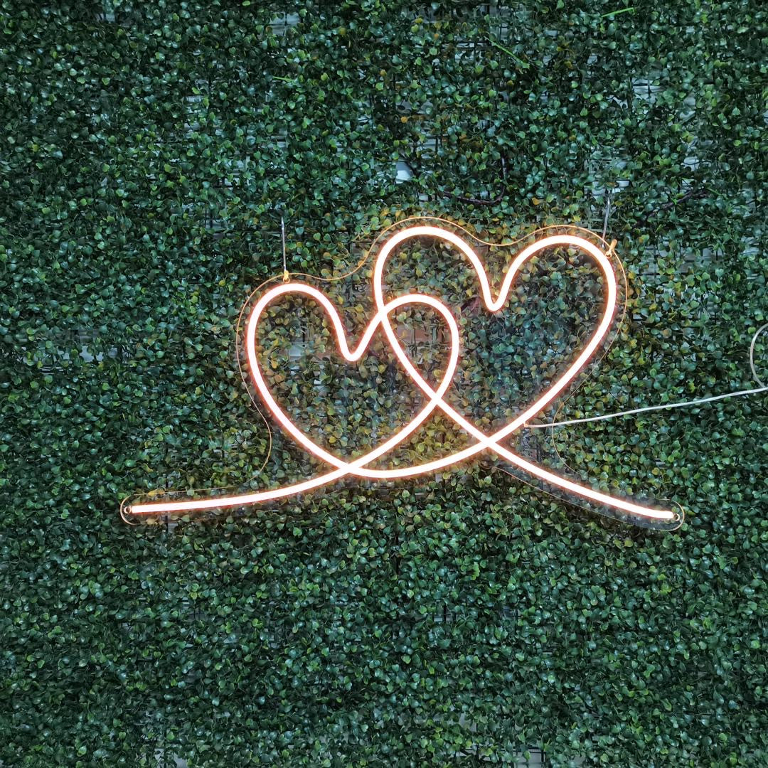 A custom neon light of an orange interlocking heart