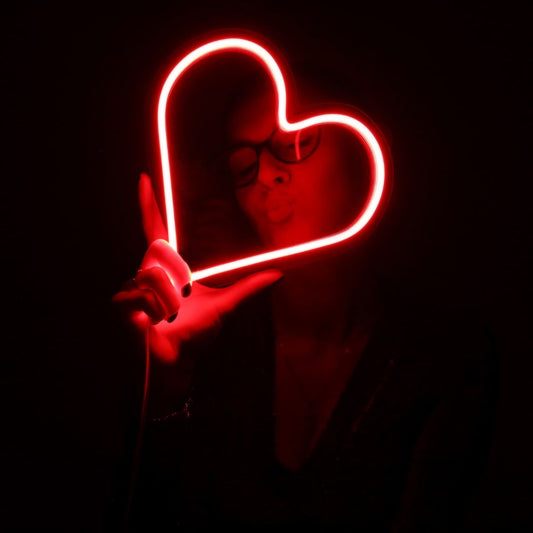 A custom neon light of a love heart being held by a woman