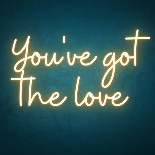 An image of a yellow custom neon sign with the text you've got the love